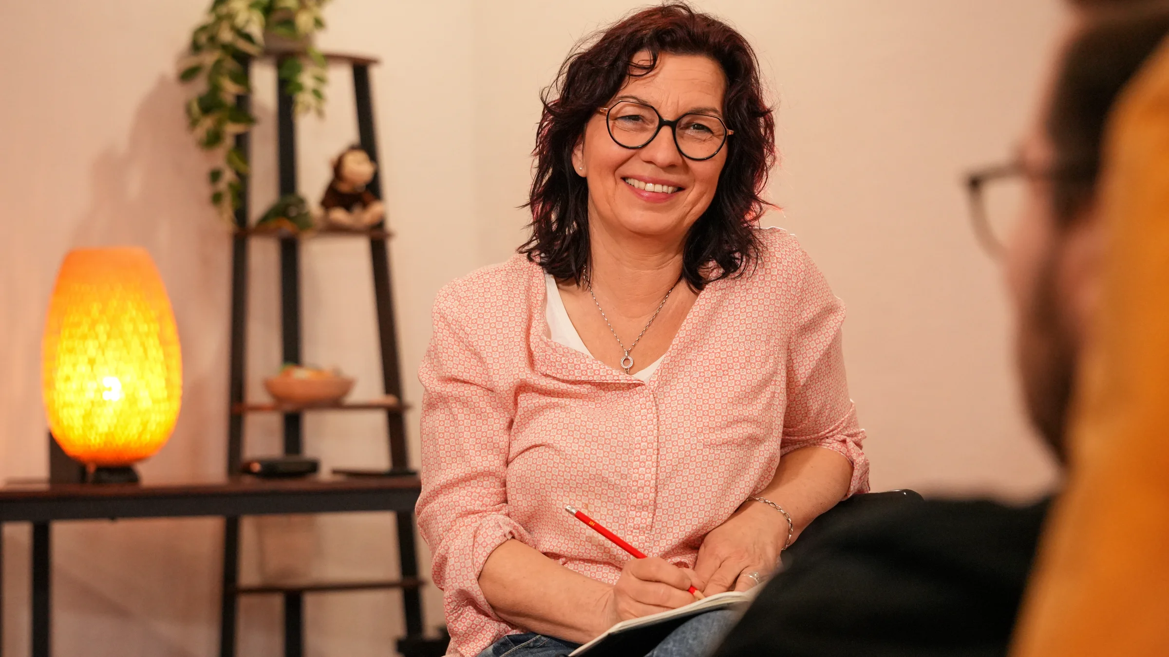 hero-hypnosepraxis-fulda-dipperz-petra-van-deyk Beratungssitzung bei Petra van Deyk, Praxis für Evolutionspädagogik. Die Therapeutin lächelt aufmerksam.